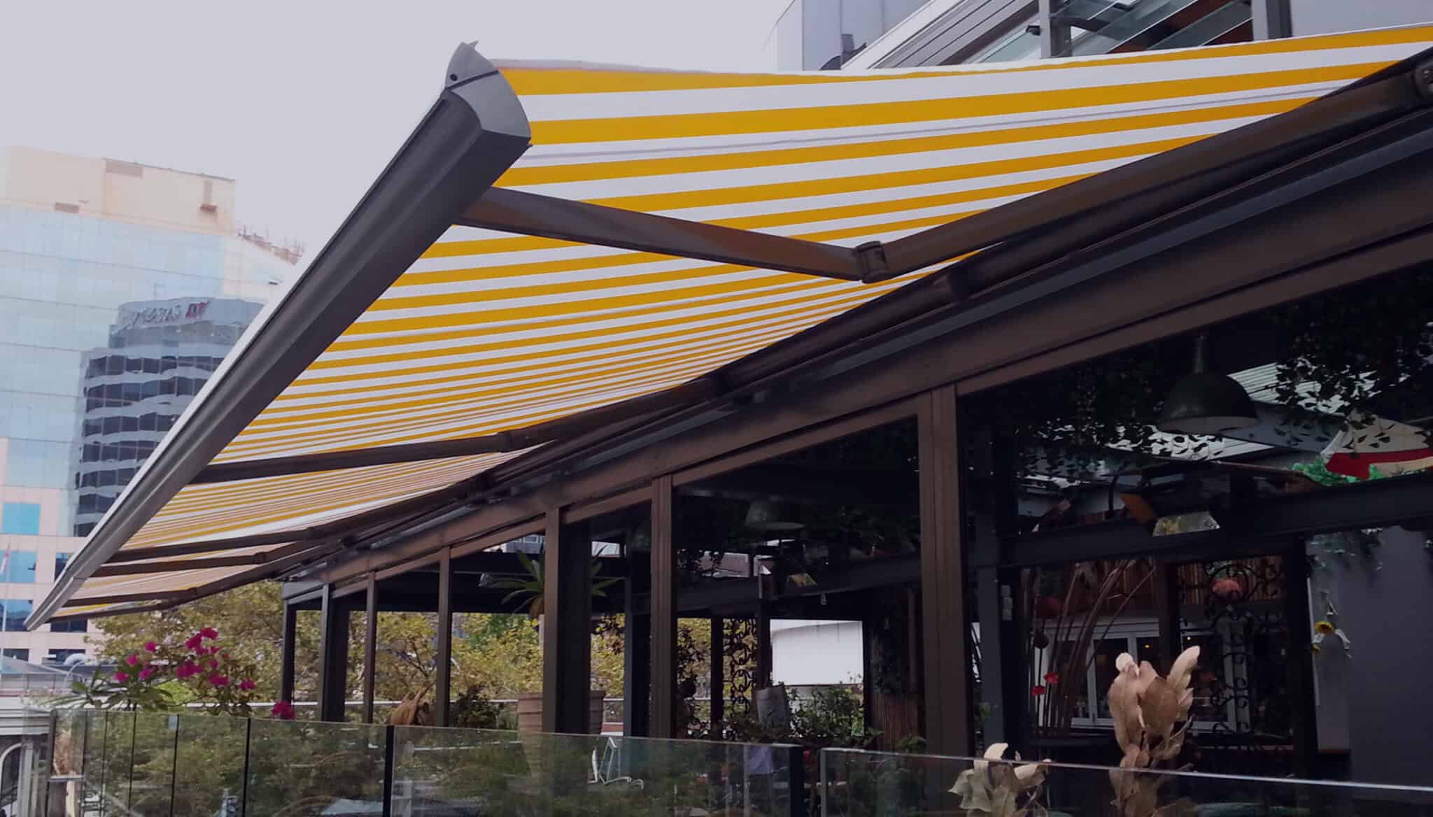 Beautiful,Light,Wooden,Side,Table,With,Bright,Green,Leaves,,Oil Outdoor cafe with yellow striped awning.